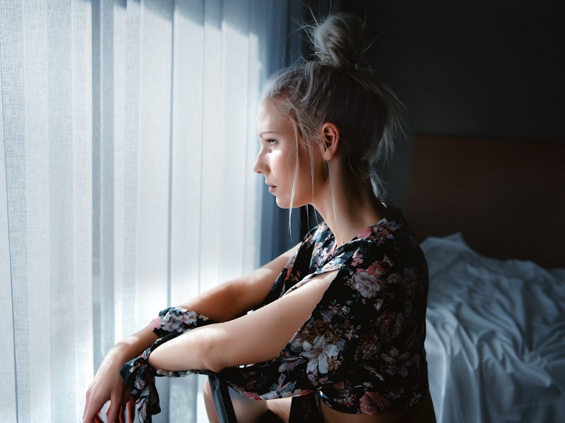 a woman in a bedroom lost in thought about how to break up with someone nicely