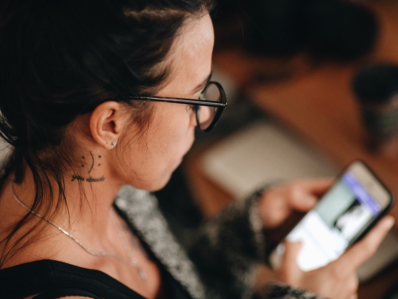 A woman looking at a mobile phone screen trying to figure out what does ghosting mean