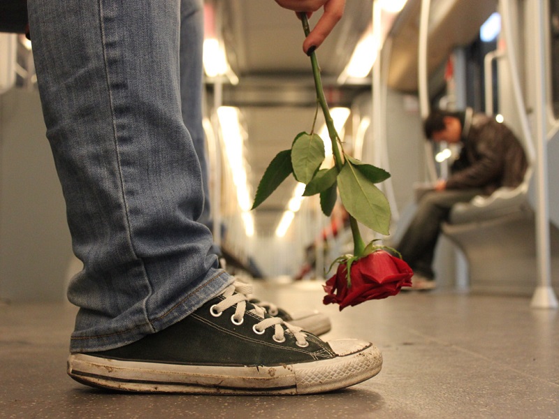 man on train holding rose thinking of long distance relationship gift ideas