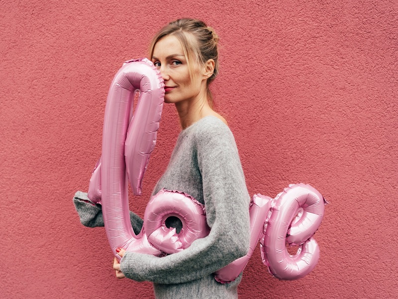 Woman smiling with love balloon on Valentine's Day 2023.