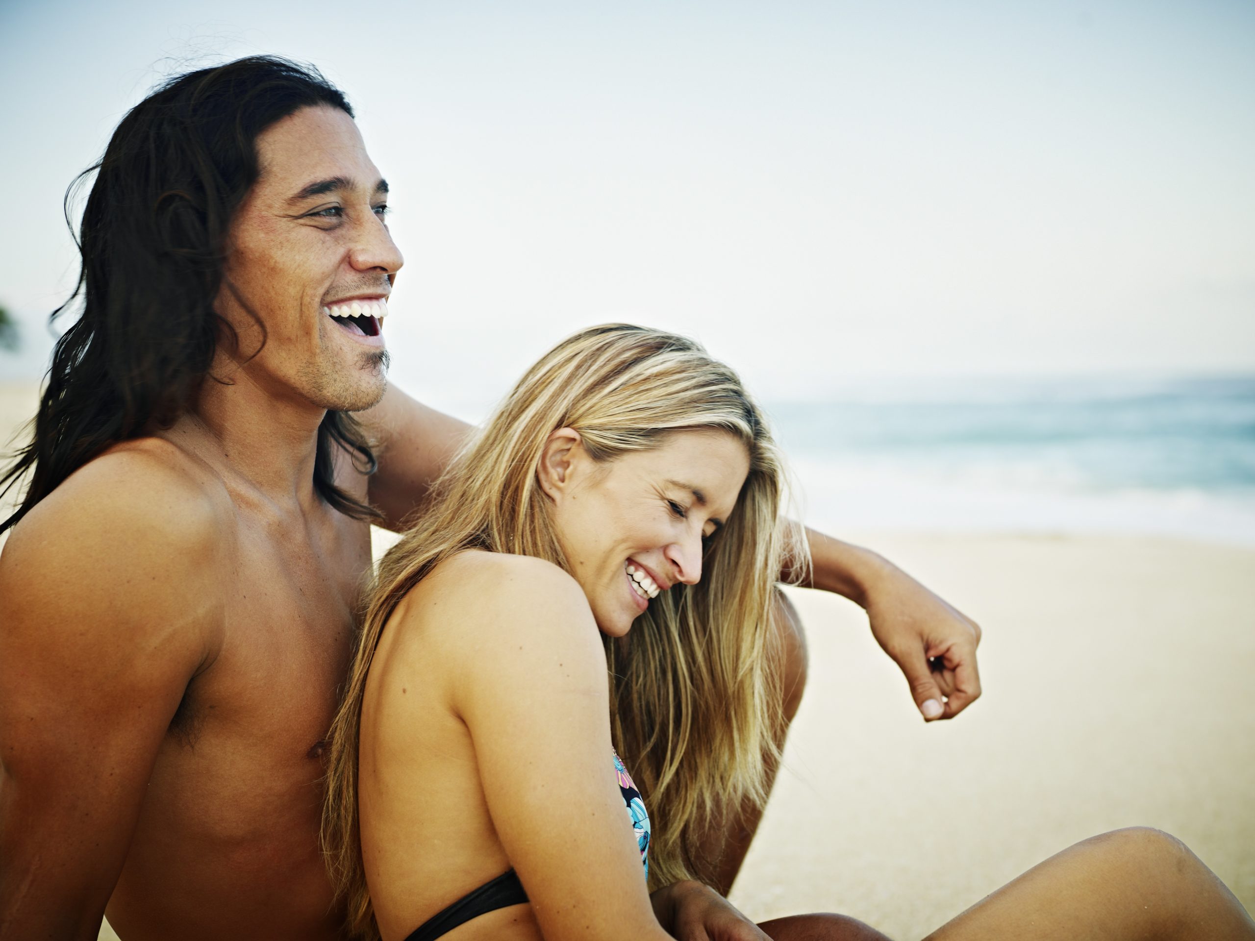 happy couple sitting on the beach in Hawaii laughing