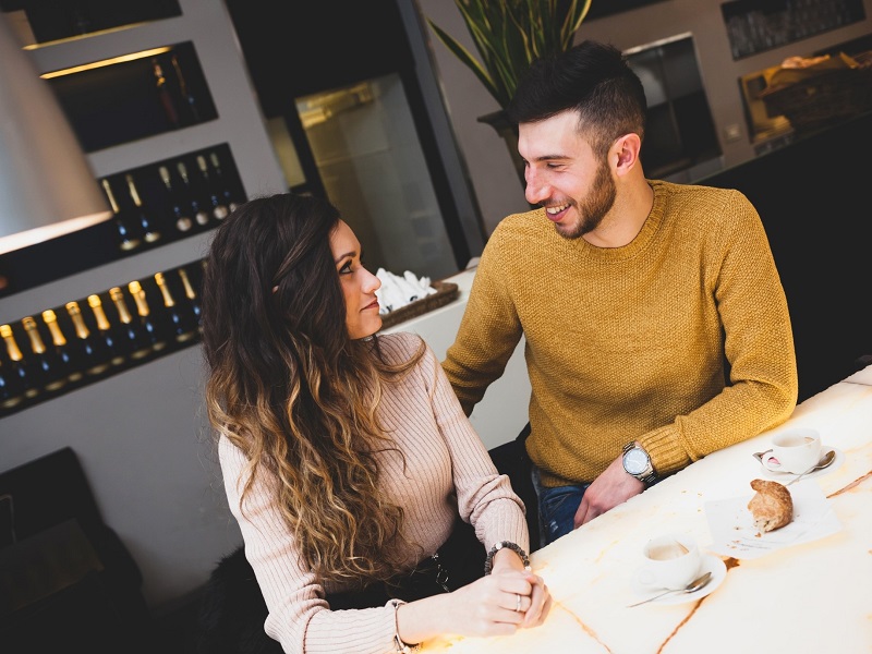 attractive couple sitting in café talking and laughing