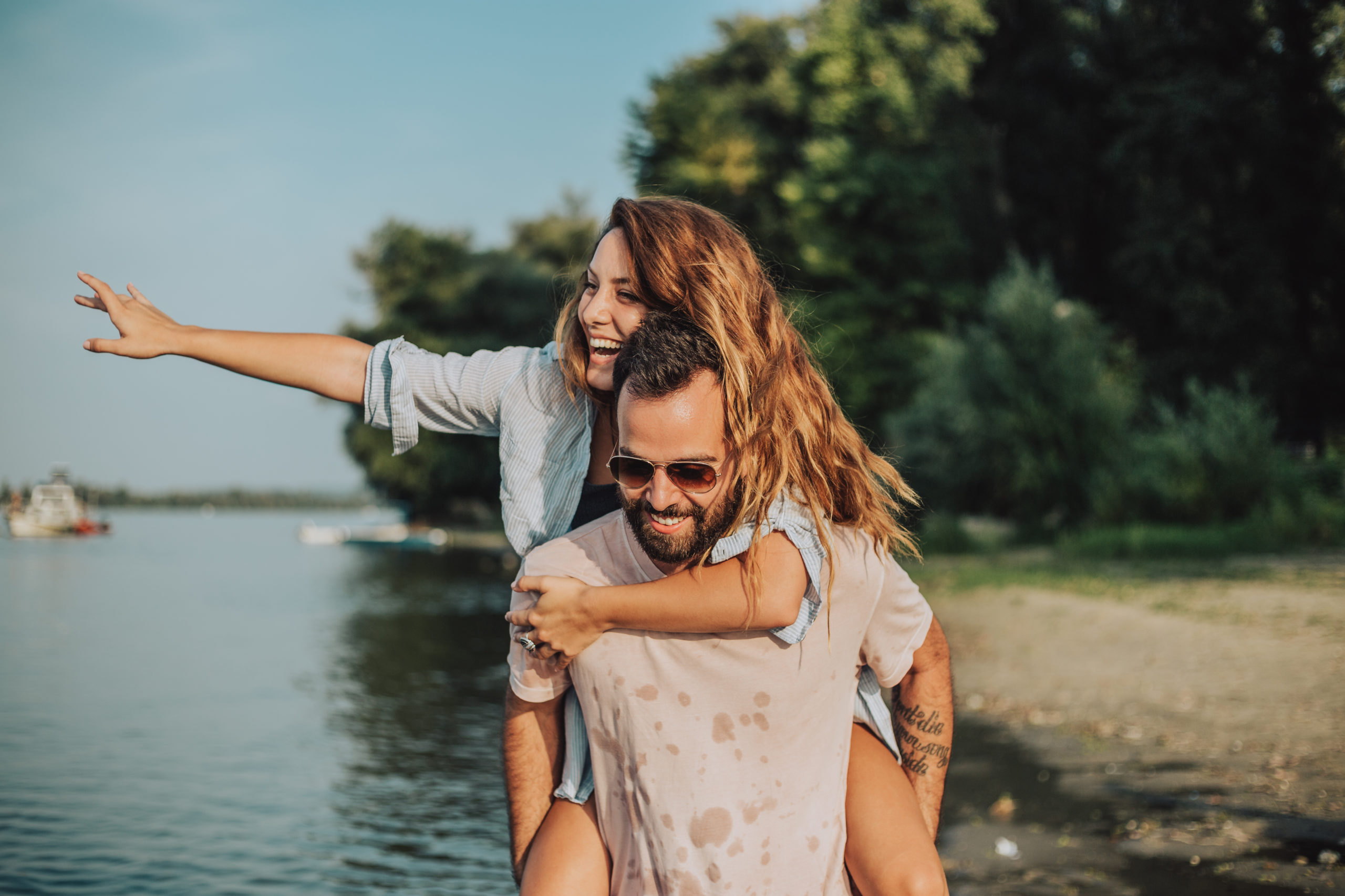 Couple dating in San Jose, laughing, smiling with the man carrying the woman on his back.