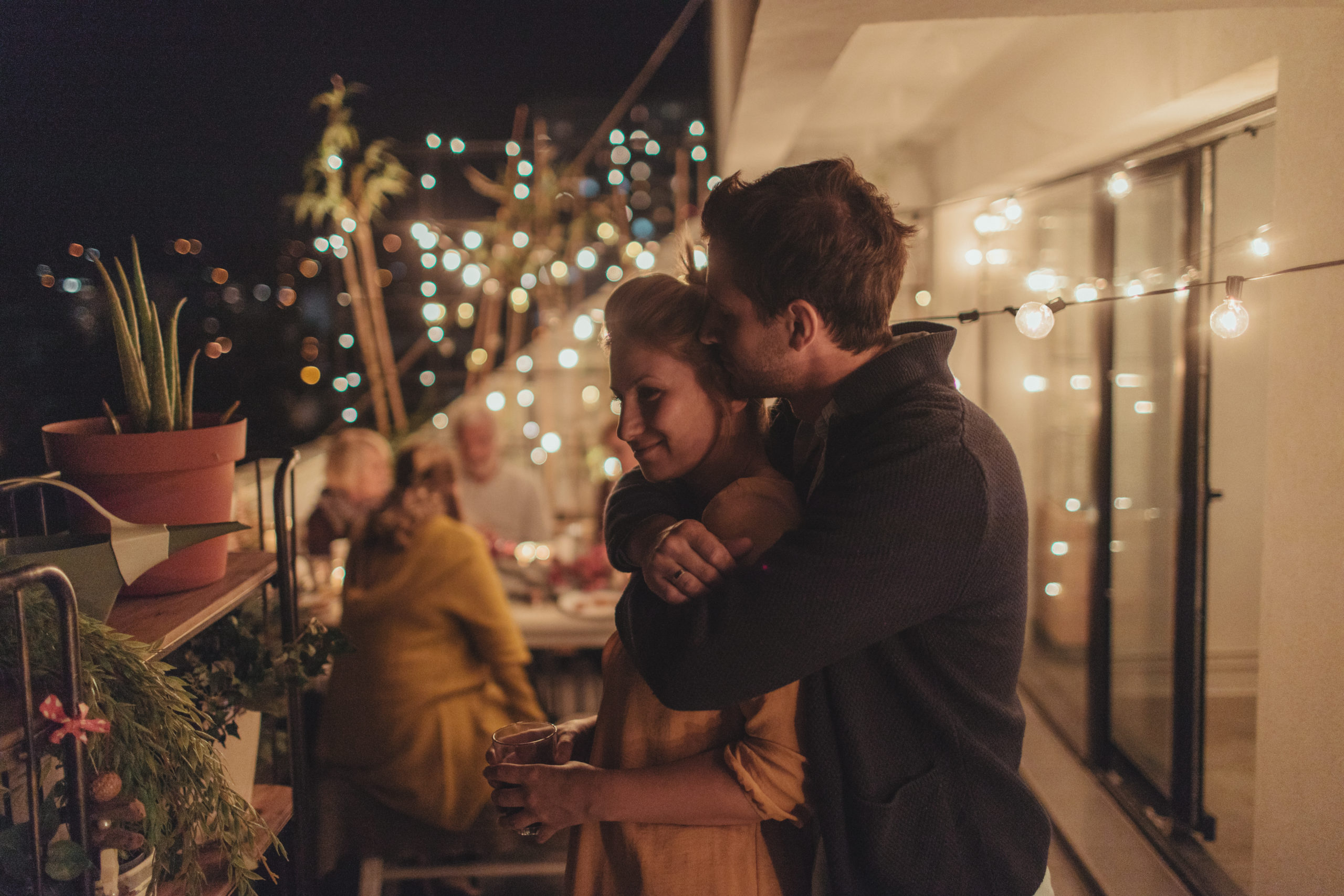 Happy couple smiling and embracing each other while having dinner outdoors and meeting the family.