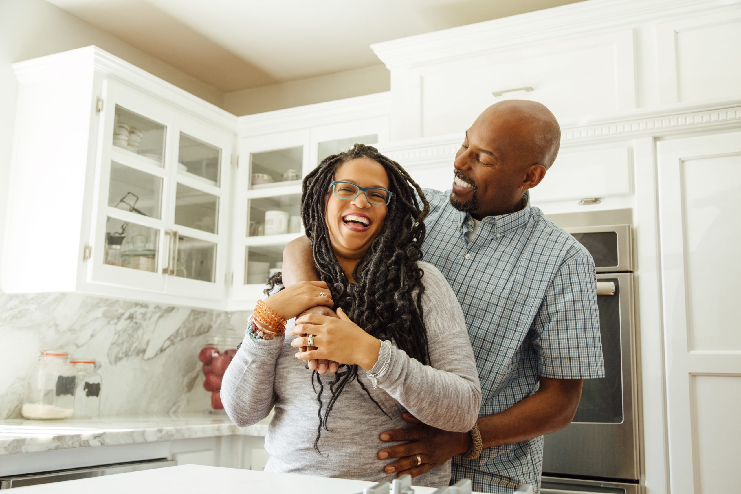 Happy, smiling couple, laughing and embracing each other in a kitchen.