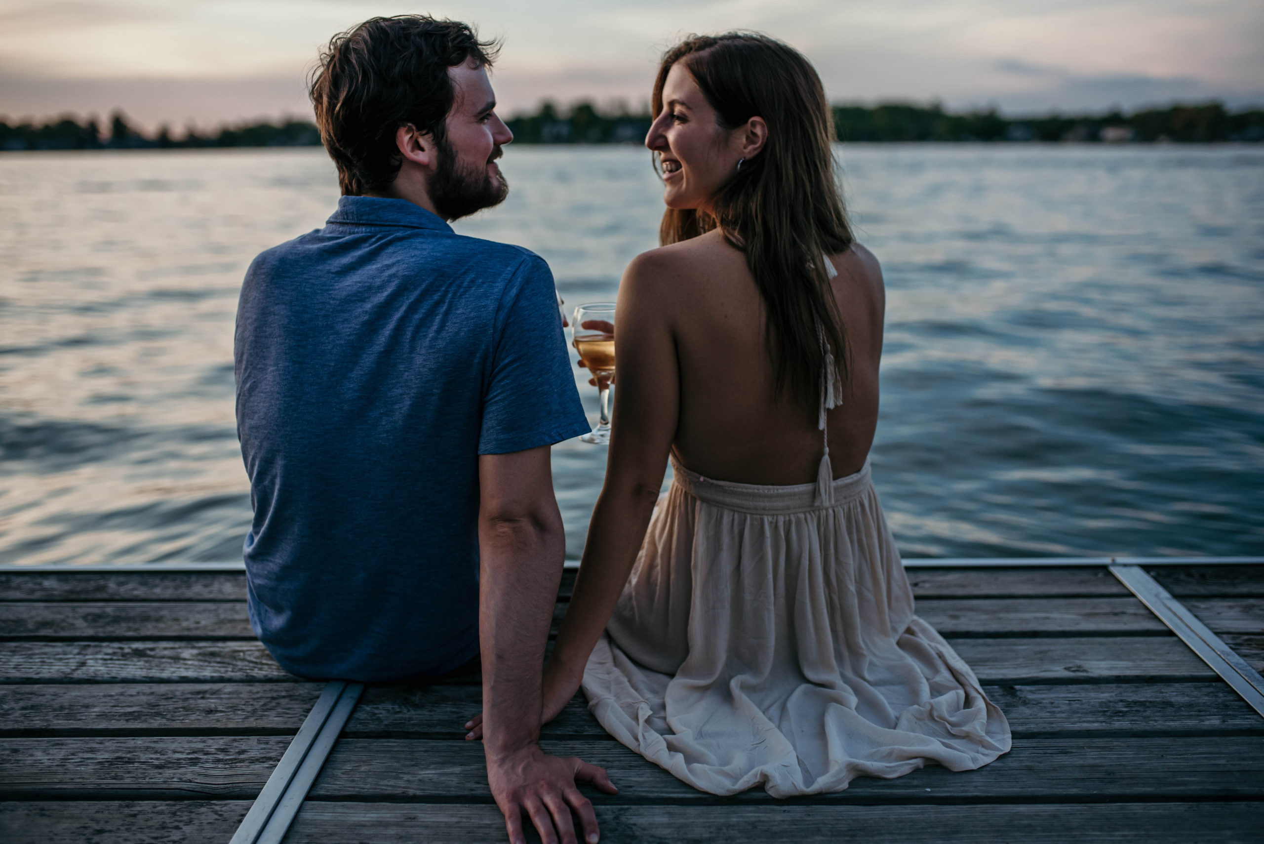 Young, happy couple sitting by the water and enjoying the sunset while dating in Tulsa.