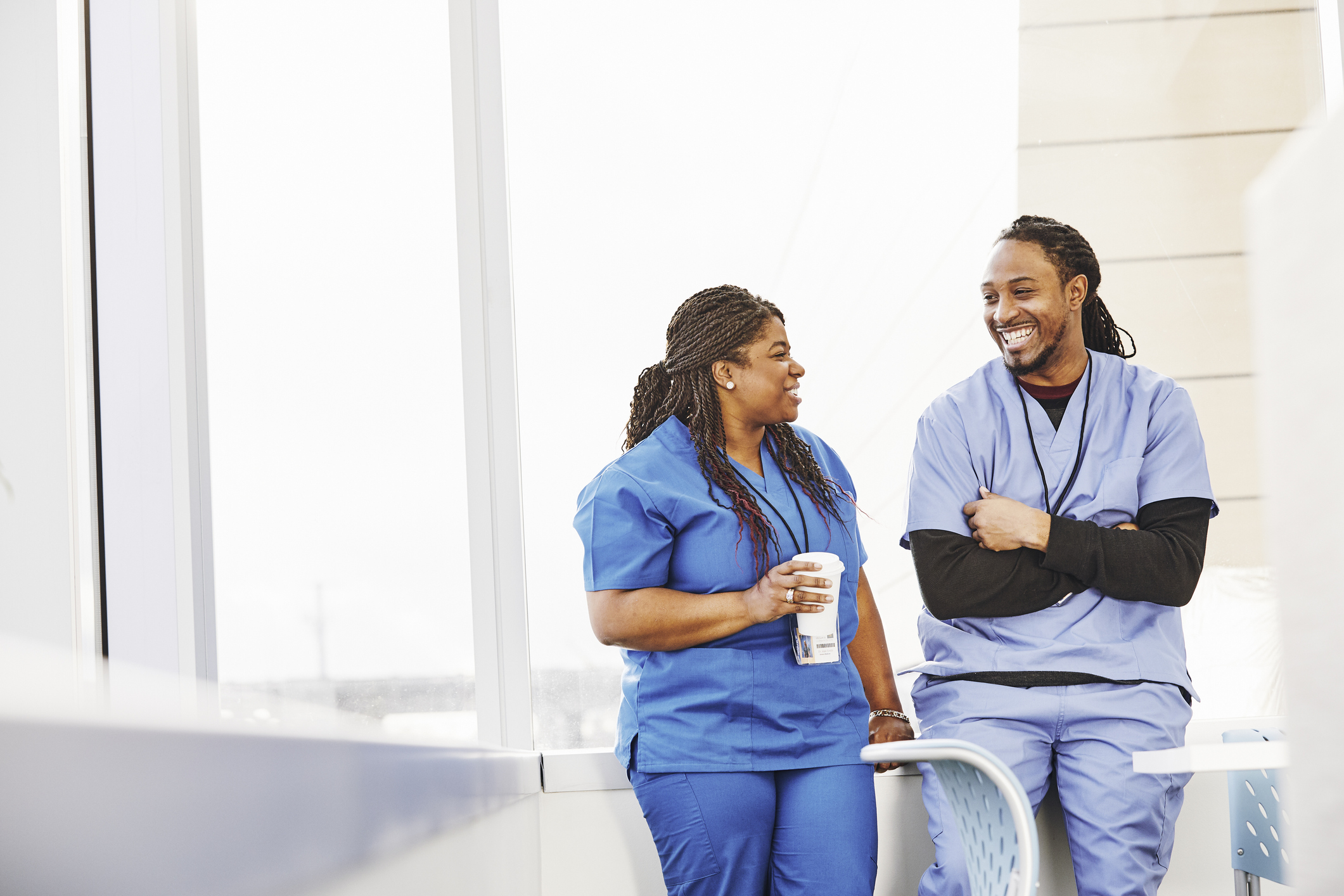Male and female nurse standing outdoors smiling and laughing while talking about dating a nurse.