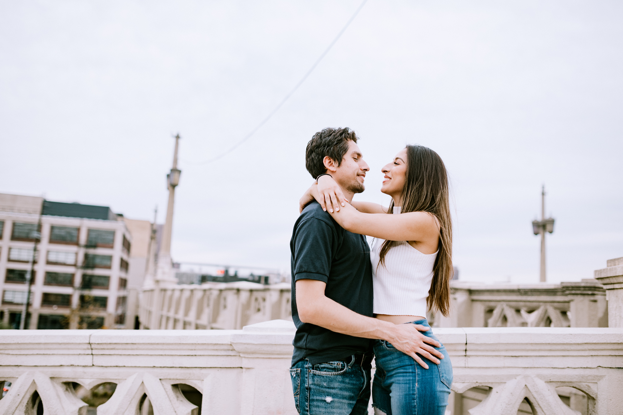 Happy Hispanic couple standing outdoors on a bridge and embracing each other after meeting on Mexican dating site.