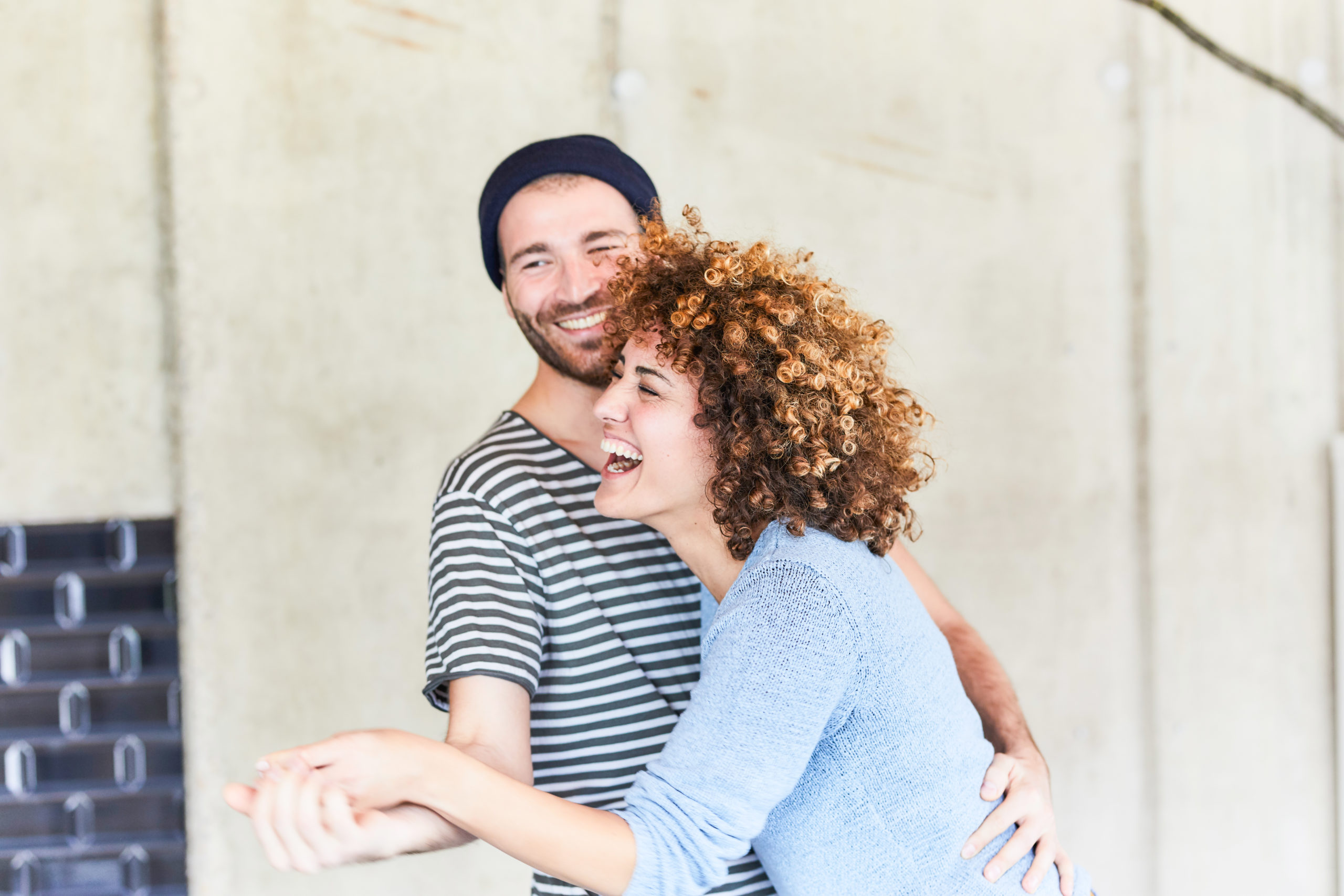 Happy couple laughing and dancing together outdoors after taking their relationship to the next level.
