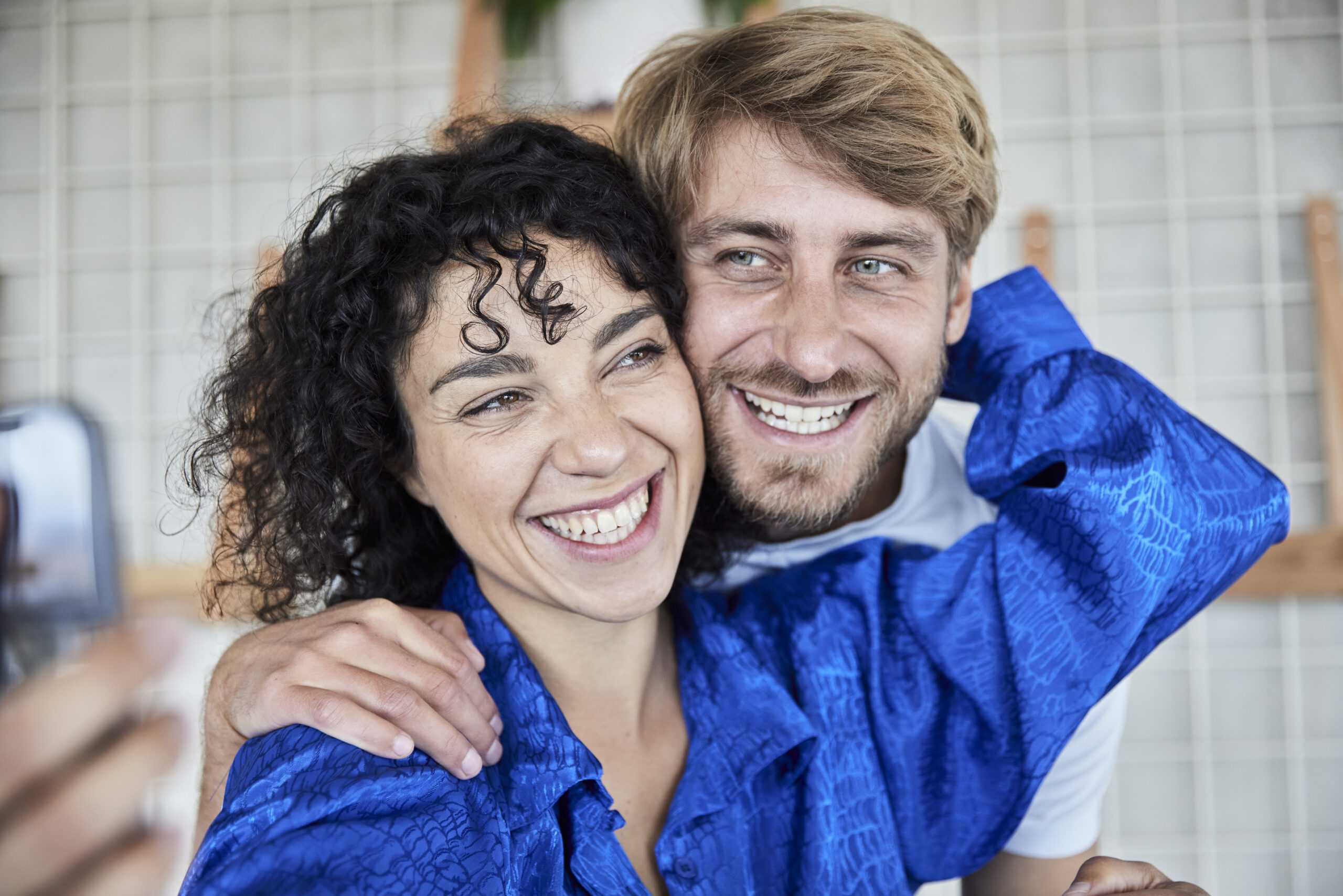 Smiling woman being hugged from behind and embraced by her smiling boyfriend while dating in Minneapolis.