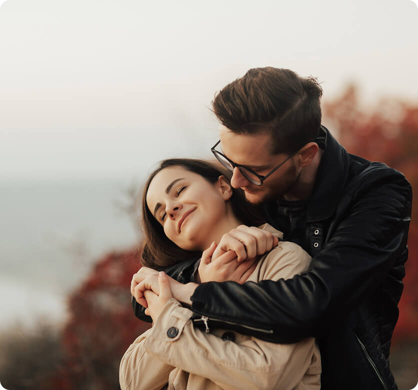 A couple shares a tender moment in an autumn landscape